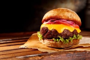 Delicious traditional cheeseburger with melted cheese and fresh salad trimmings on a juicy thick beef patty, close up low angle view with copy space